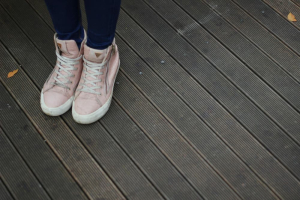 girl with pink shoes standing on a brown decking